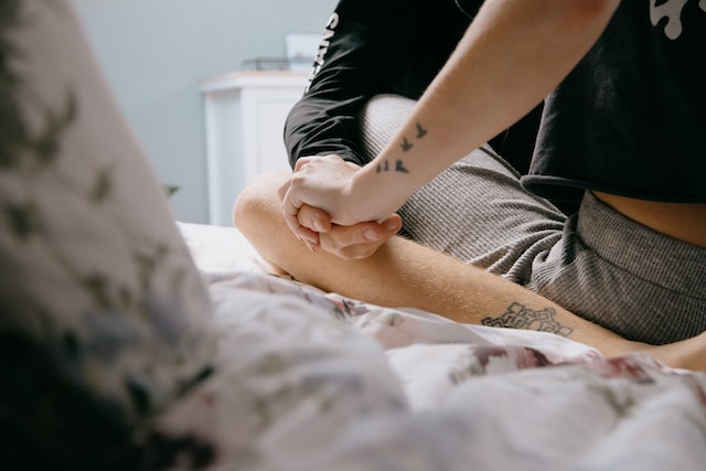 two people holding hands on a bed